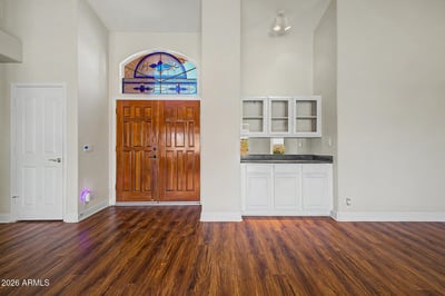 Tall ceilings, warm wood-look flooring, and decorative stained glass details create a memorable entry experience. Built-in storage cabinetry adds convenience while maintaining the home's clean, open aesthetic.
