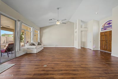 Large windows and patio doors bring in natural light while showcasing the backyard setting. The spacious layout and vaulted ceilings create a bright and welcoming atmosphere throughout the main living area.