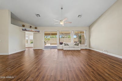 Sliding glass doors connect the living space to the covered patio, creating an ideal setup for entertaining. Updated flooring and soaring ceilings enhance the room's open and inviting feel.