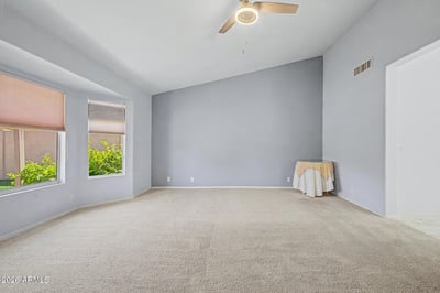 This generously sized primary suite offers plush carpeting, soothing paint colors, and abundant natural light. The comfortable design creates a peaceful space for relaxation and rest.