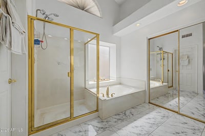 Enjoy a separate soaking tub and walk-in shower within this spacious primary bathroom. Vaulted ceilings, mirrored closet doors, and bright finishes contribute to the elegant design.