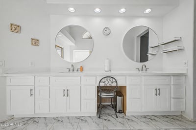 The oversized vanity provides dual sinks, abundant storage, and generous counter space. Updated finishes and bright lighting create a clean, functional, and stylish bathroom environment.