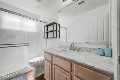 Updated finishes highlight this bathroom, including a stylish vanity, modern fixtures, and a convenient shower enclosure. The clean design enhances functionality while maintaining a fresh, contemporary feel.