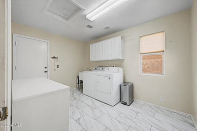 Designed for convenience, this large laundry area includes upper cabinetry, extensive floor space, and durable tile flooring. The practical layout supports storage, organization, and household efficiency.