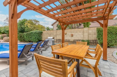 Custom pergola-covered dining area positioned beside the pool and lounge deck. This Scottsdale backyard creates the perfect atmosphere for outdoor meals and entertaining.