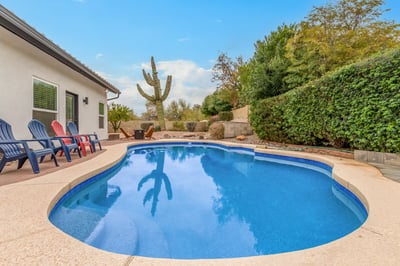 Beautiful pool surrounded by mature greenery, desert landscaping, and inviting patio seating. This Scottsdale home combines comfort, privacy, and outdoor recreation.