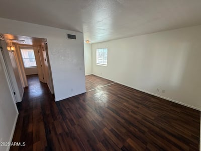Large living room with rich wood-look flooring, neutral finishes, and a bright open feel. The spacious layout creates a welcoming environment ideal for entertaining guests or enjoying everyday comfort.