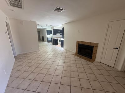 Generously sized living room featuring tile flooring, neutral tones, and a fireplace centerpiece. The flexible floor plan allows for multiple seating arrangements and comfortable daily living.