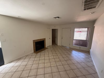 Comfortable living room centered around a charming fireplace, creating an inviting setting for relaxation. The open design and natural light enhance the warmth and livability of the space.