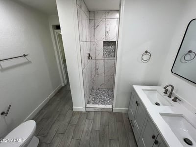 Contemporary finishes define this updated bathroom, highlighted by a spacious walk-in shower, dual vanity, and modern fixtures. The thoughtful design balances comfort and sophistication.