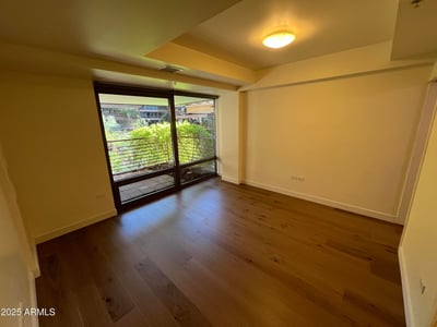Inviting bedroom with warm wood flooring, large windows, and views overlooking the private patio and landscaped surroundings. A peaceful retreat designed for relaxation and comfort.