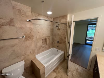 Beautiful bathroom featuring a soaking tub, full-height tile surround, and refined finishes. The spacious layout provides a spa-like atmosphere within this luxury Scottsdale condominium.