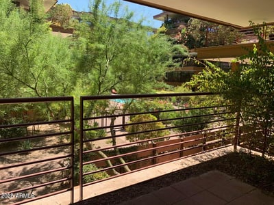 Relaxing patio outlook featuring mature desert landscaping, garden views, and community pathways. A serene environment that highlights the beauty and design of Optima Camelview Village.