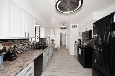 Featuring generous cabinetry, modern lighting, and durable tile flooring, this kitchen combines everyday functionality with timeless appeal. The spacious design supports busy households and entertaining alike.
