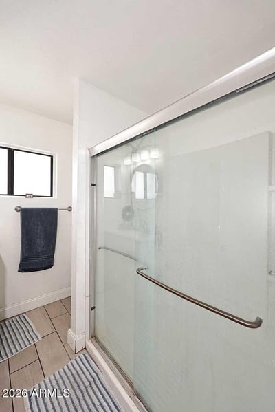 A large glass shower enclosure highlights this refreshed bathroom space. Bright finishes, natural light, and modern updates contribute to the clean and functional design.