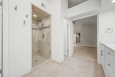 Beautifully renovated primary bathroom featuring a frameless glass walk-in shower, elegant tile surround, modern fixtures, and a clean, sophisticated design for everyday luxury.