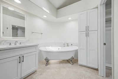 The elegant freestanding soaking tub serves as the centerpiece of this beautifully remodeled primary bathroom, complemented by custom storage, designer finishes, and a bright, airy atmosphere.