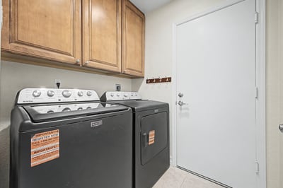 Practical laundry room with built-in upper cabinetry, dedicated washer and dryer space, and convenient storage to simplify daily household tasks.