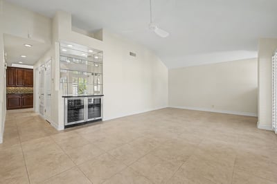 Spacious living area with dramatic vaulted ceilings, built-in beverage center, oversized tile floors, and an open layout designed for entertaining and everyday comfort.