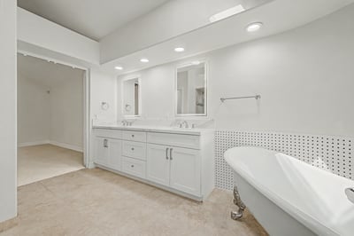 Bright primary bath featuring dual vanities, quartz countertops, custom cabinetry, and a freestanding soaking tub. Thoughtfully updated with timeless finishes and abundant natural light.
