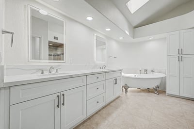 Spacious primary bathroom with dual sinks, custom cabinetry, quartz counters, and a luxurious freestanding soaking tub. Designed to provide both style and functionality in a relaxing setting.
