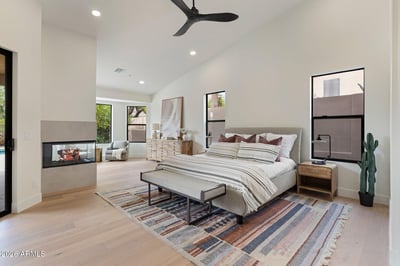 Spacious owner's suite with soaring ceilings, a contemporary fireplace, sitting area, and beautiful backyard views. Thoughtfully designed for luxury, comfort, and everyday living in this Scottsdale home.