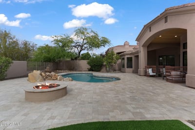 Expansive backyard with a custom fire pit, sparkling pool, spacious entertaining patio, and covered outdoor seating. Designed to maximize Scottsdale's beautiful outdoor lifestyle with luxury amenities.