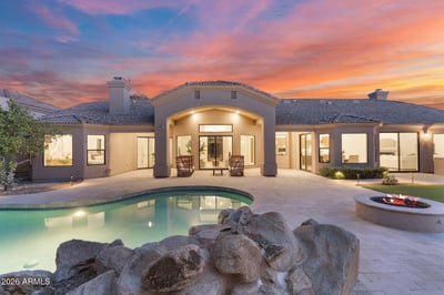 Resort-inspired backyard featuring a sparkling swimming pool, fire pit, natural rock accents, expansive patio, and covered outdoor living area. A perfect Scottsdale retreat for entertaining, relaxing, and enjoying Arizona's year-round sunshine.