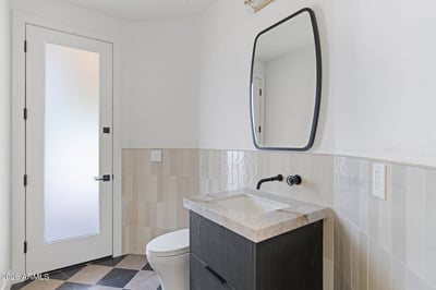 Contemporary guest powder room featuring a floating vanity, premium stone countertop, designer mirror, and sleek black fixtures. Thoughtful finishes complement the home's modern Scottsdale design.