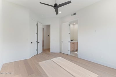 Comfortable guest bedroom with wide-plank flooring, modern ceiling fan, and direct access to a private bath. This Scottsdale home offers bright living spaces and premium finishes throughout.