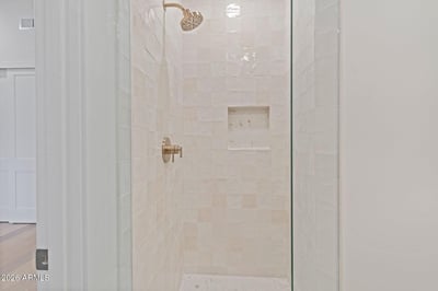 Bright walk-in shower with premium tile finishes, frameless glass, and built-in niche for convenience. This beautifully appointed Scottsdale home offers luxurious bathrooms and designer upgrades.