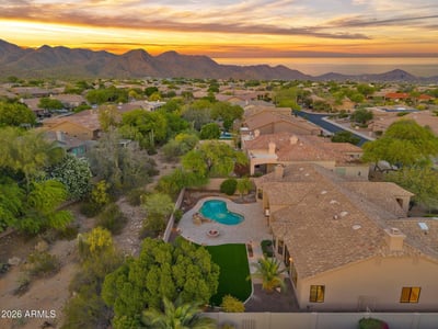 Elevated aerial highlighting the private backyard retreat, resort-style pool, expansive entertaining patio, and bordering desert wash. This Scottsdale property offers peaceful outdoor living and scenic natural surroundings.