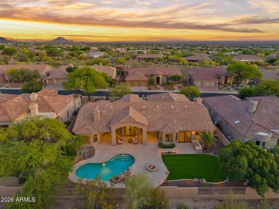 Aerial perspective showcasing the custom pool, fire pit, covered patio, artificial turf, and spacious backyard designed for entertaining. Enjoy resort-inspired living in this Scottsdale home.
