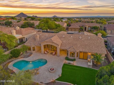 Stunning overhead view of the backyard featuring a sparkling swimming pool, custom outdoor entertaining areas, built-in BBQ, expansive travertine patio, and professionally landscaped grounds in Scottsdale.
