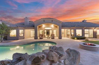 Resort-inspired backyard featuring a sparkling swimming pool, fire pit, natural rock accents, expansive patio, and covered outdoor living area. A perfect Scottsdale retreat for entertaining, relaxing, and enjoying Arizona's year-round sunshine.