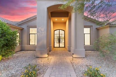 Dramatic front entrance with soaring architectural columns, paver walkway, and stylish glass doors. The welcoming entry introduces the sophisticated finishes found throughout this luxury Scottsdale home.