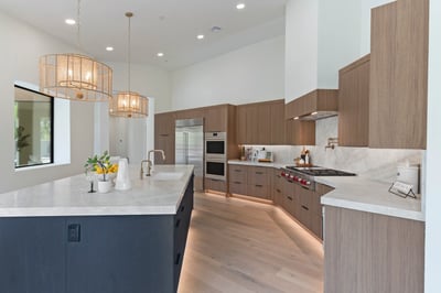 Sophisticated gourmet kitchen with a large waterfall island, Wolf range, Sub-Zero refrigerator, custom cabinetry, quartz countertops, and designer lighting. An ideal space for cooking and entertaining.