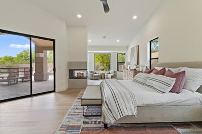 Beautiful primary bedroom featuring a fireplace, comfortable sitting area, large sliding glass doors, and peaceful backyard views. This luxurious Scottsdale retreat offers a relaxing atmosphere with elegant finishes and direct access to the outdoor living spaces.