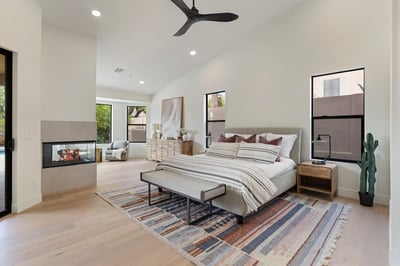 Spacious owner's suite with soaring ceilings, a contemporary fireplace, sitting area, and beautiful backyard views. Thoughtfully designed for luxury, comfort, and everyday living in this Scottsdale home.