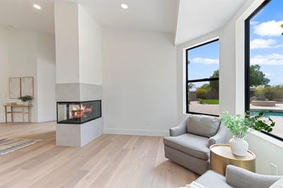 Comfortable sitting space adjacent to the primary bedroom featuring a sleek fireplace, oversized windows, and tranquil outdoor views. Perfect for reading, relaxing, or enjoying quiet mornings.