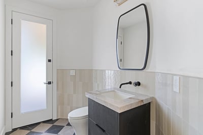 Contemporary guest powder room featuring a floating vanity, premium stone countertop, designer mirror, and sleek black fixtures. Thoughtful finishes complement the home's modern Scottsdale design.