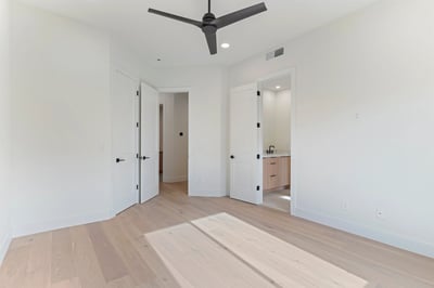 Comfortable guest bedroom with wide-plank flooring, modern ceiling fan, and direct access to a private bath. This Scottsdale home offers bright living spaces and premium finishes throughout.