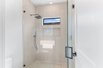 Beautiful guest shower featuring floor-to-ceiling tile, frameless glass enclosure, rainfall showerhead, and contemporary fixtures. A refined upgrade that complements this Scottsdale home's luxurious design.