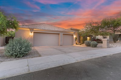 Welcoming front exterior featuring a spacious three-car garage, attractive desert landscaping, and timeless curb appeal. This Scottsdale residence blends elegance with everyday functionality.