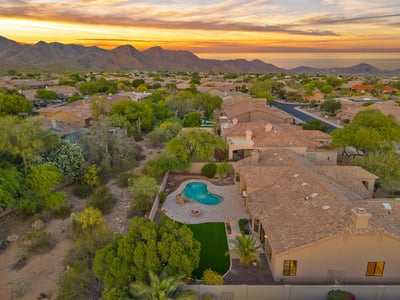 Elevated aerial highlighting the private backyard retreat, resort-style pool, expansive entertaining patio, and bordering desert wash. This Scottsdale property offers peaceful outdoor living and scenic natural surroundings.