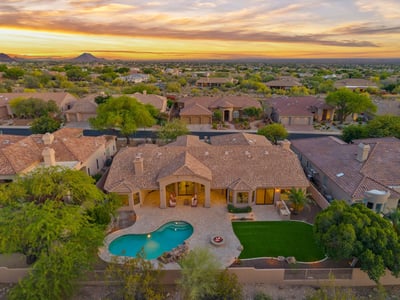 Aerial perspective showcasing the custom pool, fire pit, covered patio, artificial turf, and spacious backyard designed for entertaining. Enjoy resort-inspired living in this Scottsdale home.