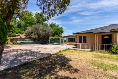 This alternate angle highlights the opposite side of the front yard, featuring lush green space, mature shade trees, and the inviting exterior of the home. The oversized lot provides plenty of room to enjoy outdoor living while maintaining excellent curb appeal.