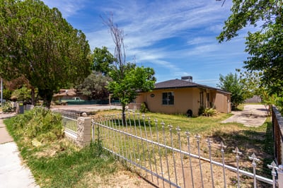 The corner view of the front yard showcases mature trees, attractive landscaping, a covered porch, and the home's spacious lot. This Mesa property offers great curb appeal, outdoor flexibility, and a welcoming first impression.