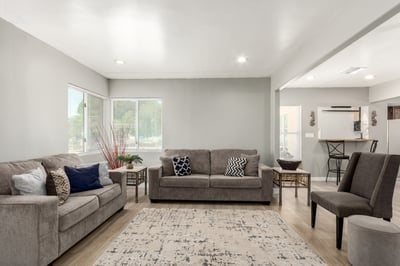 Large windows fill this gathering space with natural light while updated flooring and neutral finishes provide a move-in-ready appeal. The open design enhances comfort and flexibility throughout the home.