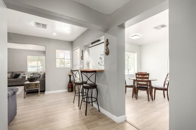 This angle showcases the breakfast bar, open hallway, and seamless connection between the living spaces and kitchen. Bright finishes and updated flooring create a welcoming flow throughout this remodeled Mesa home.
